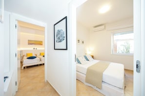 A hotel room with a bed, a bedside table, a wall-mounted picture, and a window.
