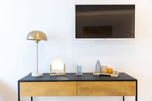 A black desk with a gold lamp, a mirror, a reed diffuser, and decorative items.