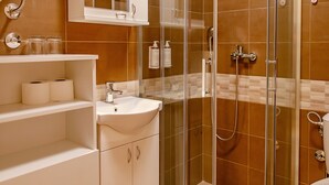Een moderne badkamer met een douchecabine van glas, een witte wastafel met wasbak en een toilet.