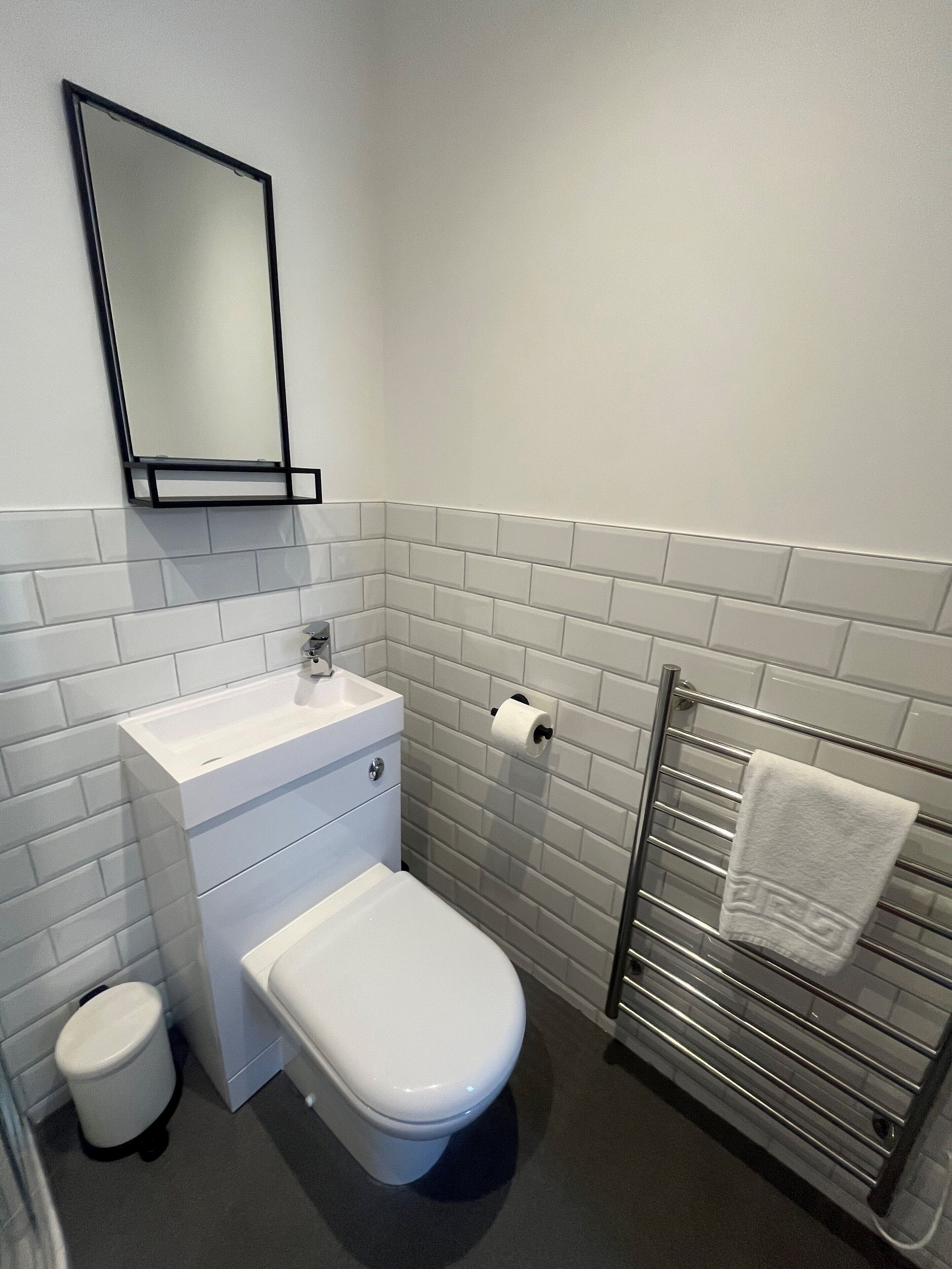 Un baño pequeño con inodoro blanco, lavabo y perchero para toallas.