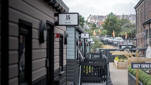 A street view with numbered buildings, a sign for '15 Red Devil', and a 'COZY TAPAS' sign. - Goodstay Lodges by Urban Space (Barry)
