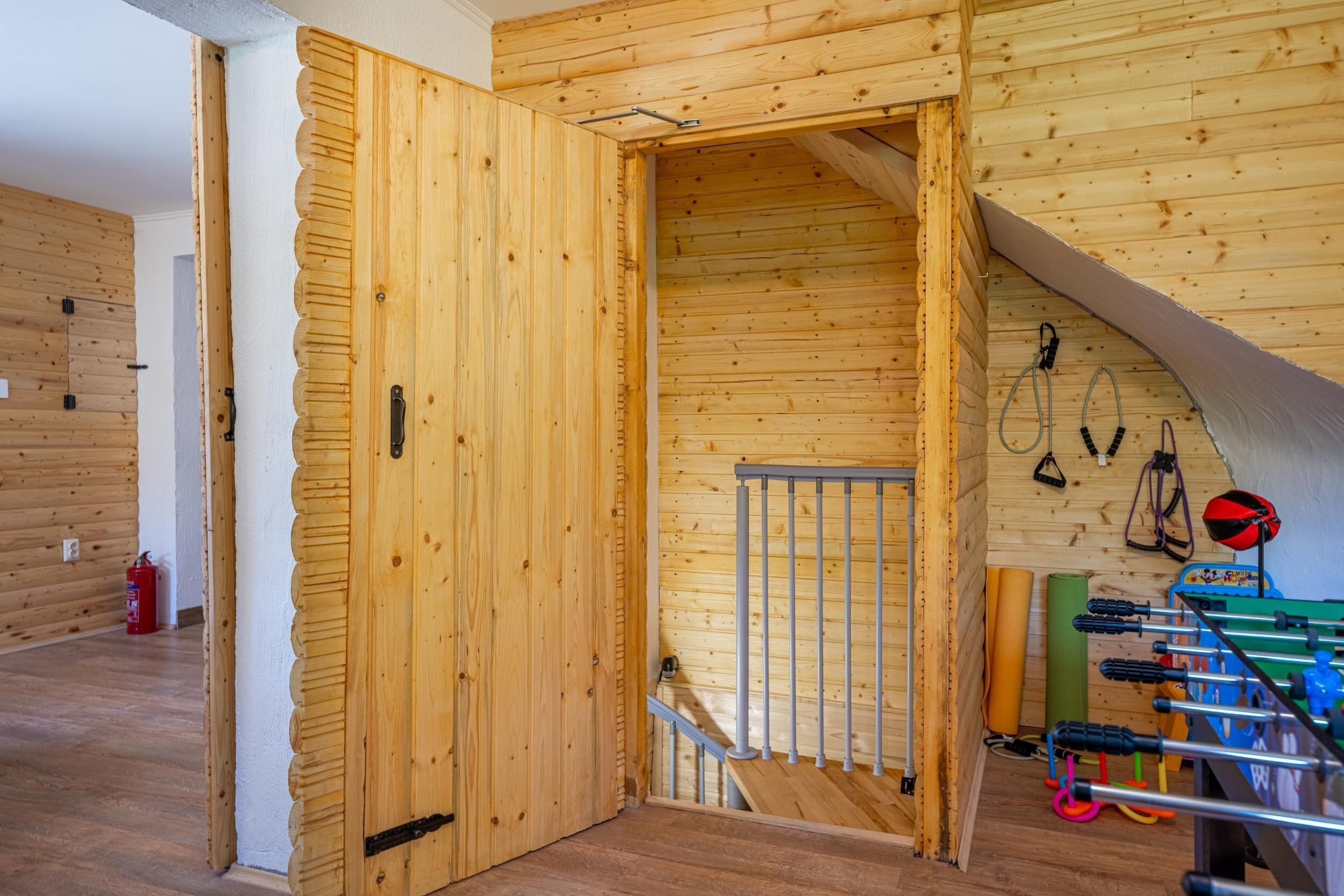 Ein Holzinnenraum mit Treppe, einer Tür und an der Wand befestigtem Trainingsgerät.