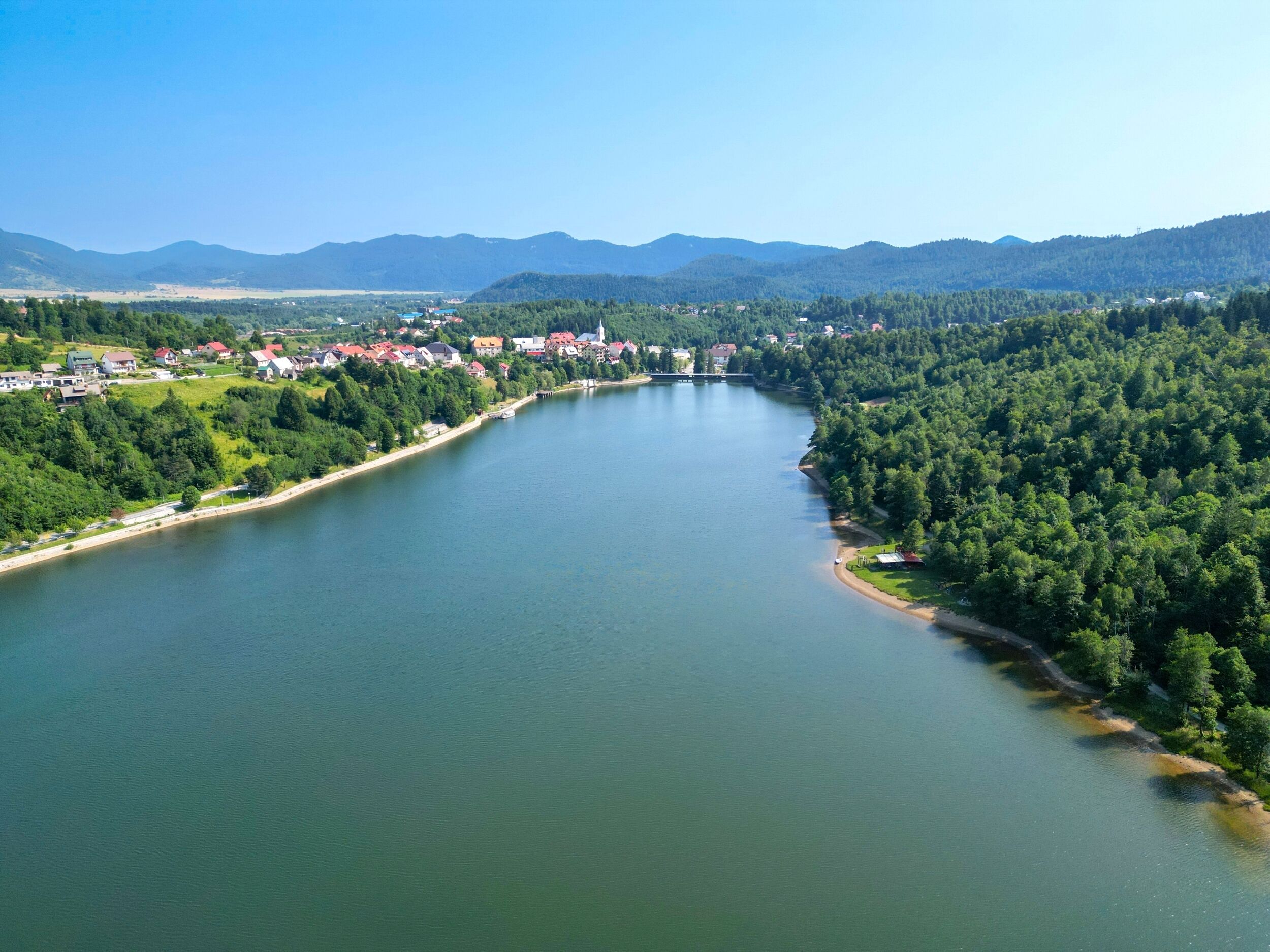 A river with a town on one side and a forest on the other.