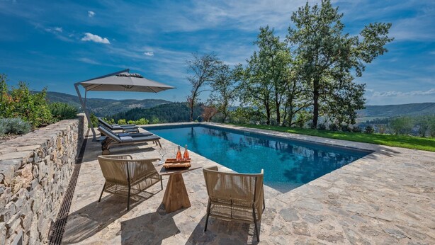 A swimming pool with lounge chairs and a table, surrounded by stone walls and trees. - Riecine Capanna  4, Gaiole in Chianti, Siena and Chianti (Gaiole in Chianti)