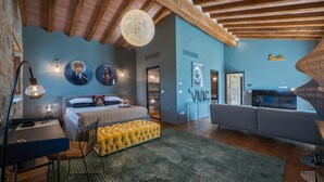 A modern bedroom with a bed, a yellow ottoman, a desk, and a sofa. - Riecine Capanna  4, Gaiole in Chianti, Siena and Chianti (Gaiole in Chianti)
