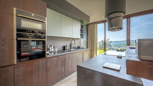 A modern kitchen with a built-in oven, a sink, and a large window overlooking a scenic landscape. - Riecine Capanna  4, Gaiole in Chianti, Siena and Chianti (Gaiole in Chianti)