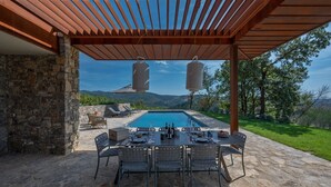 An outdoor dining area with a pool, stone walls, and a view of the mountains. - Riecine Capanna  4, Gaiole in Chianti, Siena and Chianti (Gaiole in Chianti)