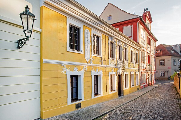 Une rue pavée bordée de bâtiments historiques, caractérisés par des détails architecturaux raffinés et une façade jaune.