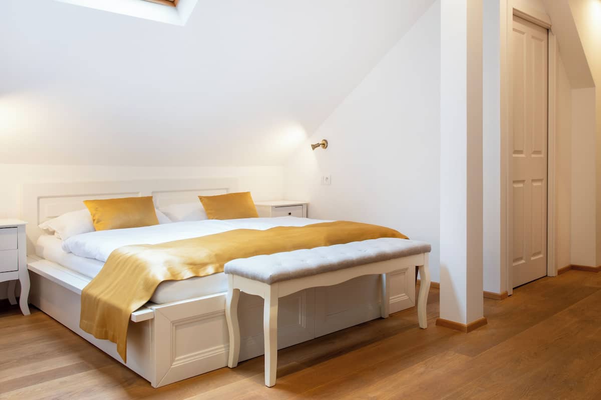 A bedroom with a bed, bedside tables, a bench, and a door.