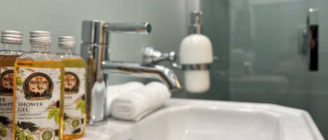 Un lavamanos de baño con dos botellas de gel de ducha etiquetadas como "Spa Beerland" y un dispensador de jabón blanco.