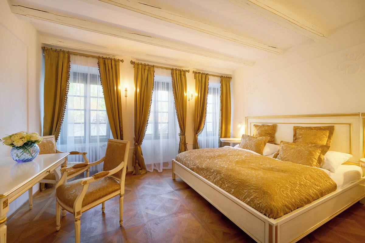A bedroom with a large bed, a desk, and a chair.