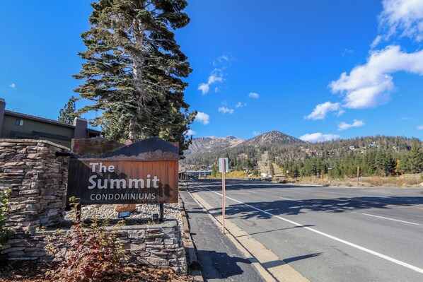 A sign for "The Summit Condominiums" with a clear view of the road and mountains in the background.