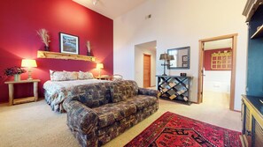A bedroom with a bed, a patterned sofa, a red carpet, a console table, and a bookshelf. - Large Family Home. Washer/Dryer, Pool Table & Gas Grill. Mountain Views (Mammoth Lakes)
