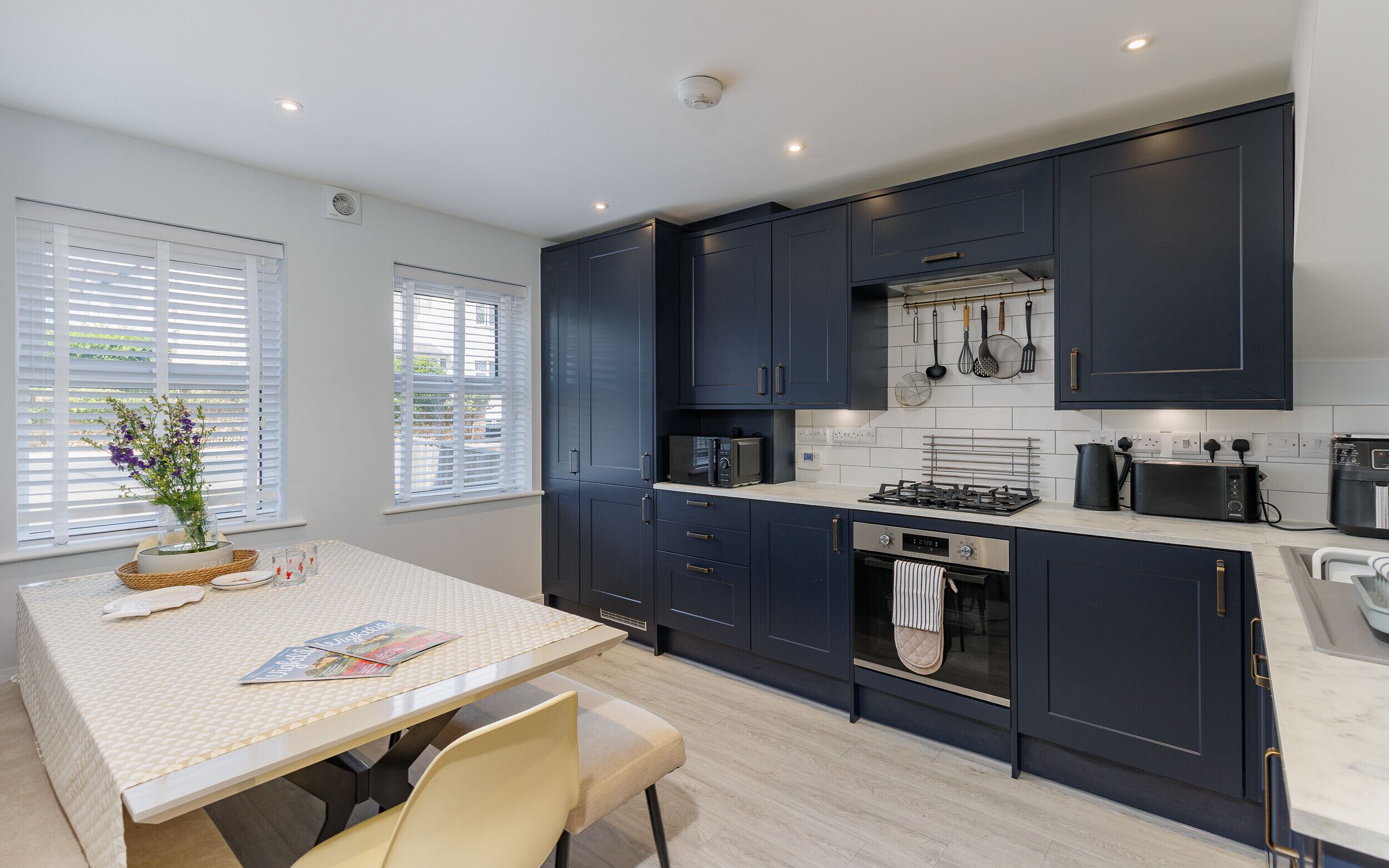 A modern kitchen with dark cabinets, a microwave, stove, and various utensils.