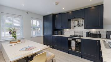 A modern kitchen with dark cabinets, a microwave, stove, and various utensils.