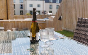Une bouteille de vin et trois verres sur une table en verre dont le plateau présente un motif tissé.