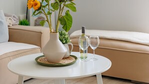Une table ronde blanche, ornée d’un vase rempli de tournesols, d’une bouteille de vin et de deux verres à vin.