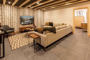 A modern living room with a sofa, coffee table, and a TV mounted on the wall. - Ski Chalet Bonnabelle, Hot tub, garden, parking (Chamonix)