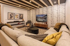 A modern living room with a sectional sofa, a coffee table, a TV, and a bookshelf. - Ski Chalet Bonnabelle, Hot tub, garden, parking (Chamonix)