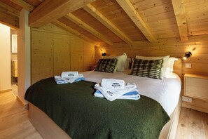 A wooden cabin bedroom with a bed, pillows, and a green blanket. - Ski Chalet Bonnabelle, Hot tub, garden, parking (Chamonix)