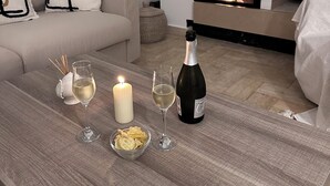 Ein gemütliches Wohnzimmer mit Kamin, einer Couch, einem Couchtisch mit Weingläsern, einer Kerze und einer Champagnerflasche.