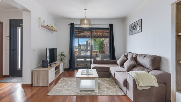 Een moderne woonkamer met een bank, een salontafel, een televisie en een balkon met uitzicht.