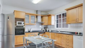 Een moderne keuken met houten kastjes, een roestvrijstalen koelkast, een magnetron en een vaatwasser.