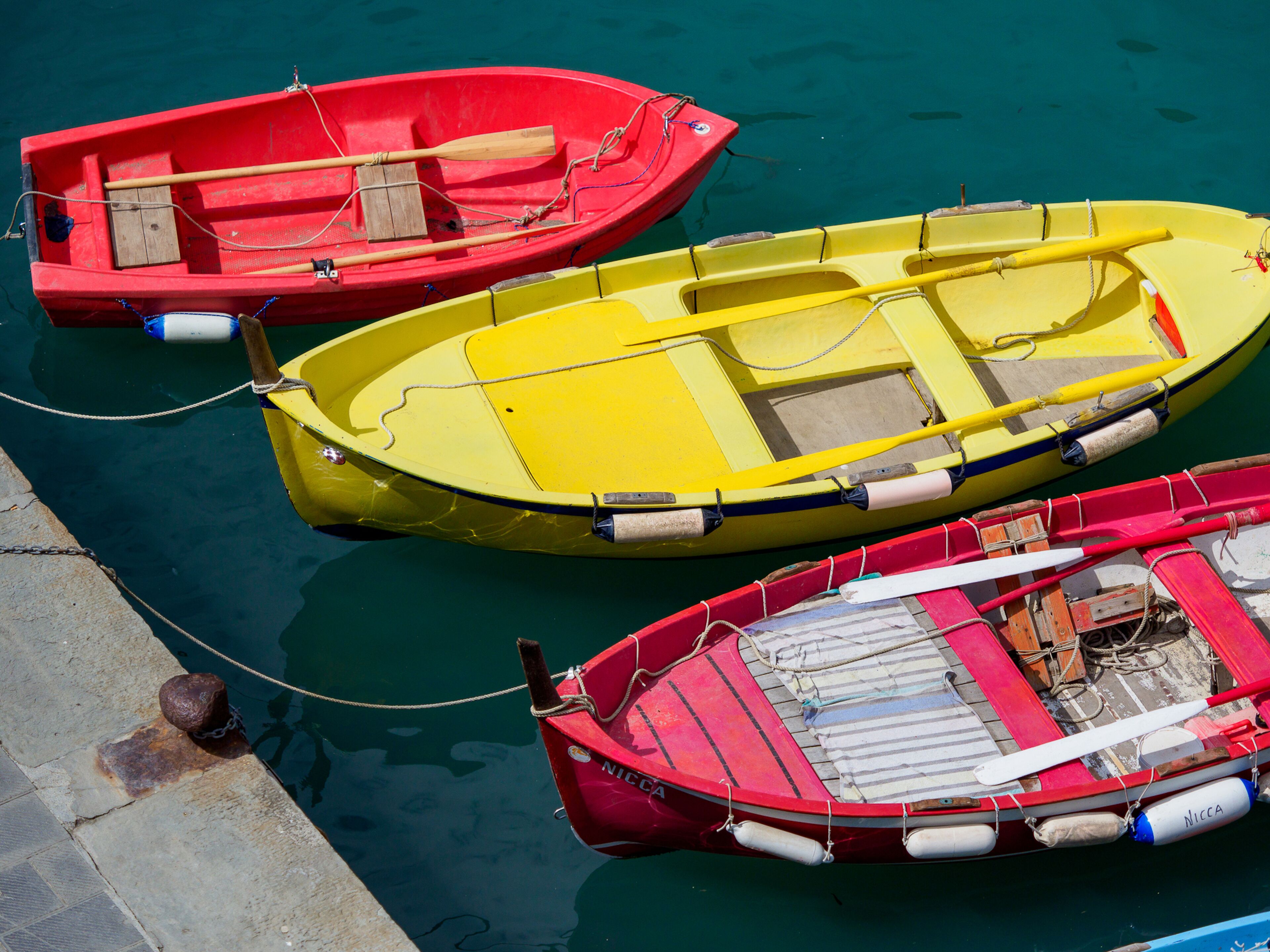 Tres pequeñas embarcaciones amarradas a un muelle.