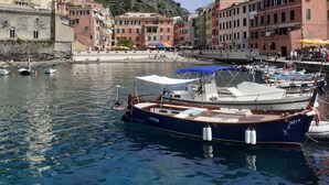 Una marina con barche ormeggiate, un edificio in pietra e edifici colorati sullo sfondo.