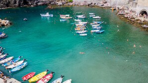 Un porto con numerose imbarcazioni ormeggiate e persone che nuotano nell'acqua.