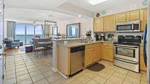 A spacious kitchen with a central island, stainless steel appliances, and wooden cabinets. - Oceanfront Crescent Beach 1K 2Q - Crescent Shores - 1609 (North Myrtle Beach)