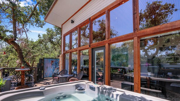 Un área de hidromasaje con terraza de madera, puertas de cristal y mobiliario exterior.