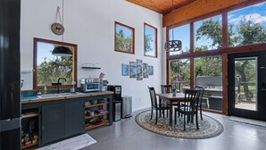 Una cocina moderna con comedor, ventanas amplias y techo de madera.