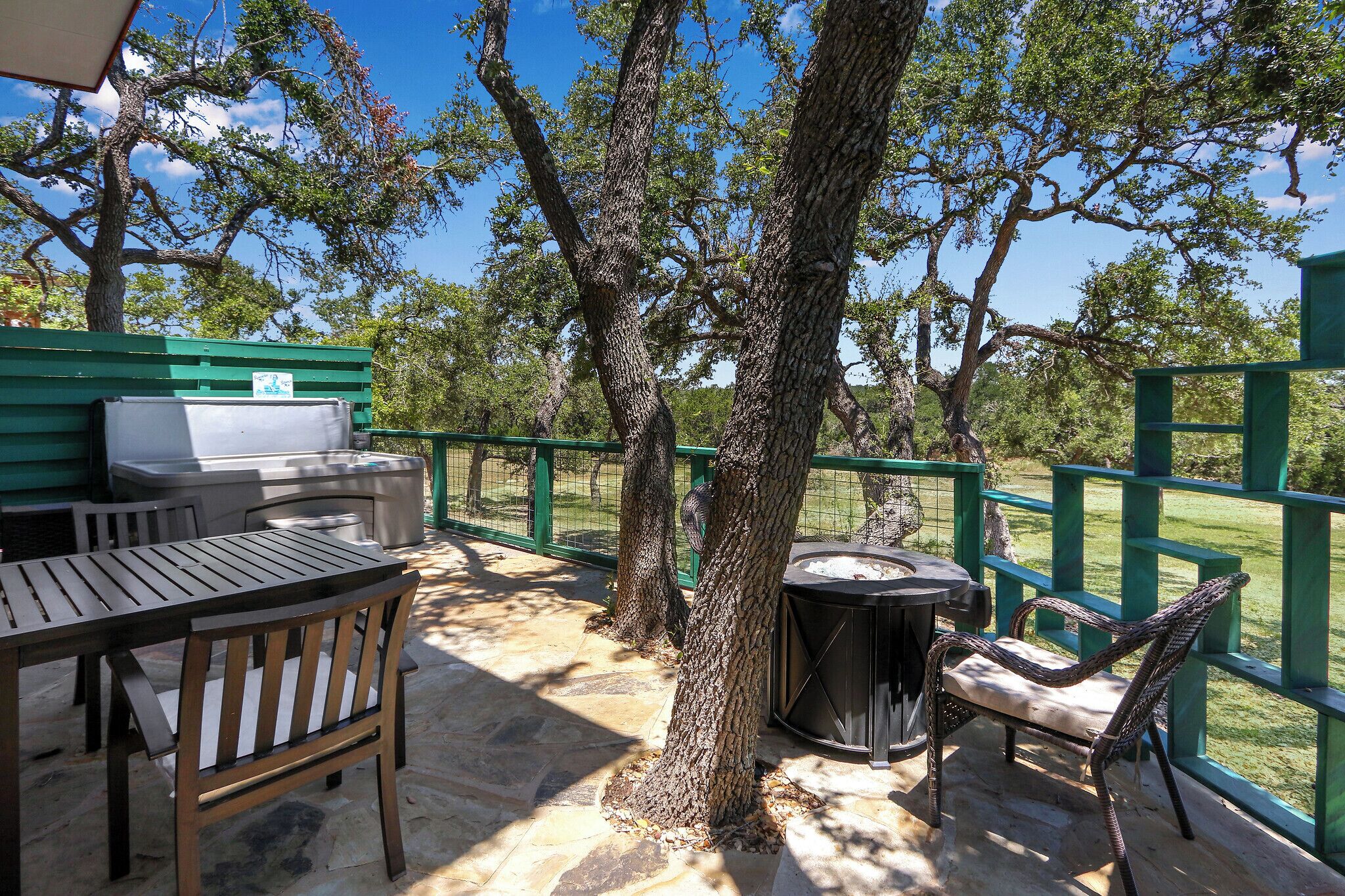 Una terrazza esterna con tavolo e sedie, un braciere e un recinto verde.