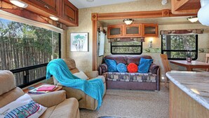 A cozy RV interior with a seating area, kitchenette, and large windows. - Windmill Ranch- Glamping Star RV  I Hot tub, stargazing (Wimberley)