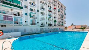 A swimming pool adjacent to a multi-story residential building with balconies.