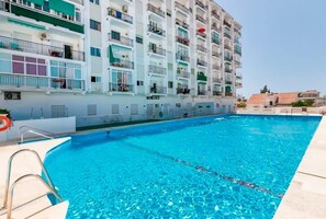 A swimming pool adjacent to a multi-story residential building with balconies.