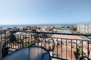 A balcony with a view of a coastal cityscape, including buildings and a clear sky.