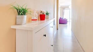 A hallway with a white counter, potted plants, and a purple couch in the background.