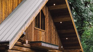 Une cabane en rondins avec une véranda, deux chaises et une petite table.