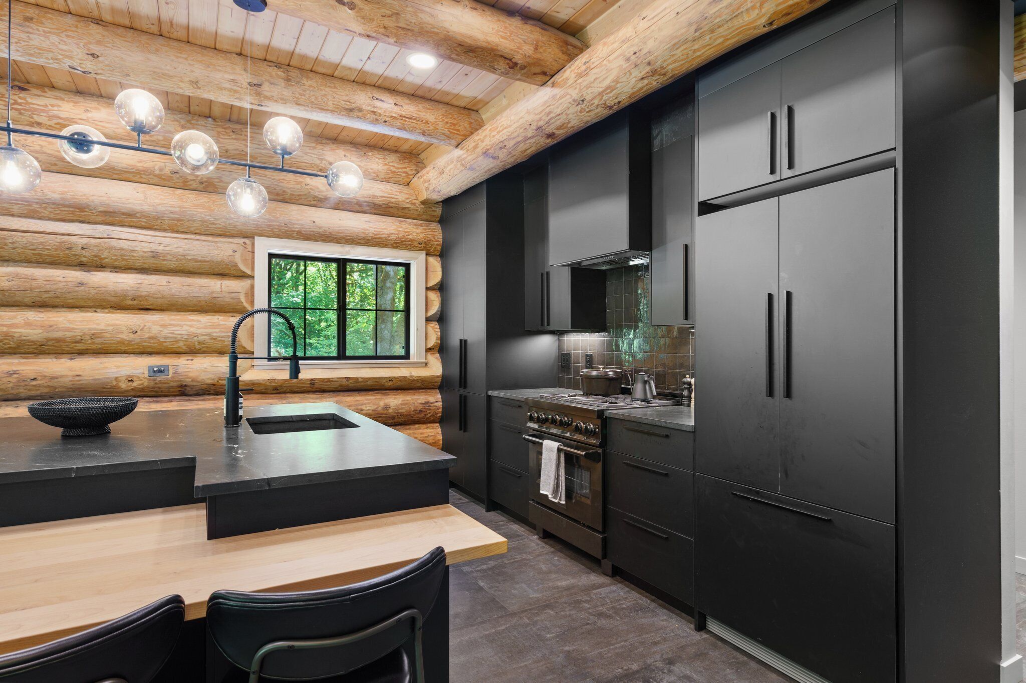 A modern kitchen with black cabinetry, a central island, and a large window.
