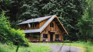 Eine Blockhütte mit Metallbedachung, umgeben von dichtem Wald.