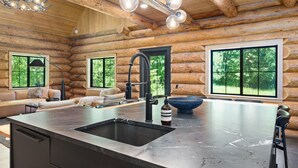 Ein modernes Blockhaus-Interieur mit Kücheninsel, großen Fenstern und einer gemütlichen Sitzecke.