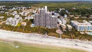 An aerial view of a coastal resort with a large hotel building, beachfront properties, and a clear view of the ocean. - Sunset Paradise 308–Corner Unit–Sleeps 8 (Santa Rosa Beach)