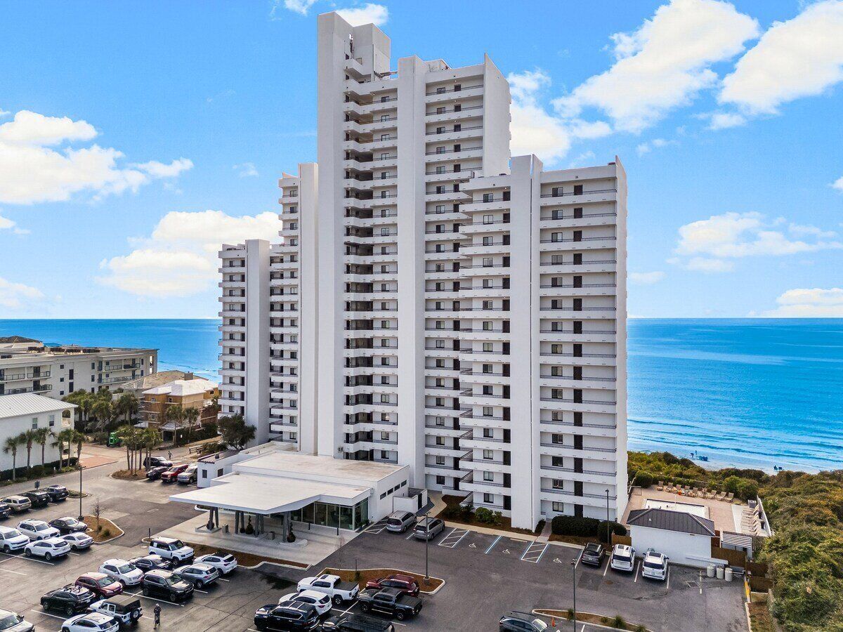 Un grand hôtel à plusieurs étages, doté d’un parking et offrant une vue sur l’océan.