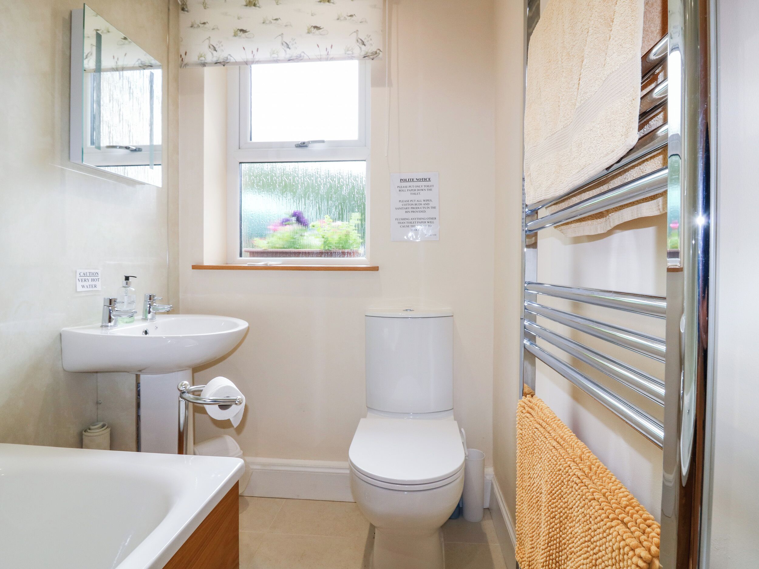 A bathroom with a sink, toilet, and a window with a view of greenery.