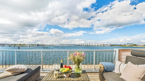Een balkon met rieten meubels, een bloemenvaas en een fles champagne.