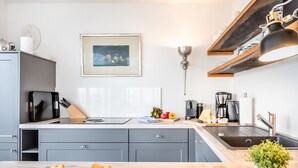 Een moderne keuken met grijze kastjes, een houten aanrecht, een spoelbak en een koffiezetapparaat.