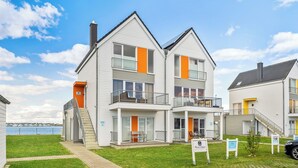Een woongebouw met twee verdiepingen, een balkon, een trap en uitzicht op het water.