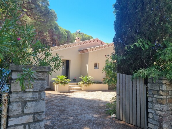 A house with a stone gate, a gravel driveway, and a wooden fence.